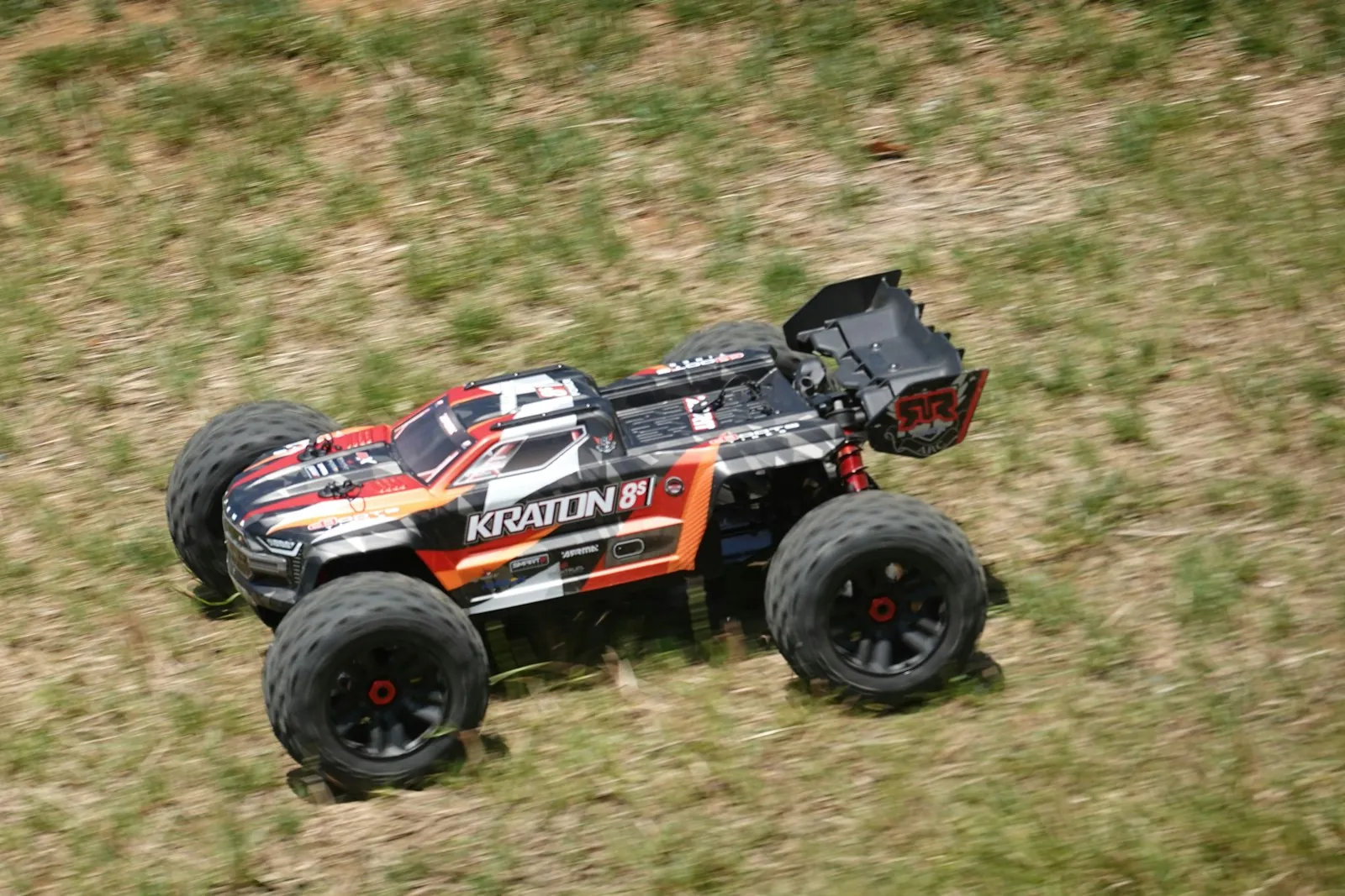 RC monster truck bashing across a grassy field